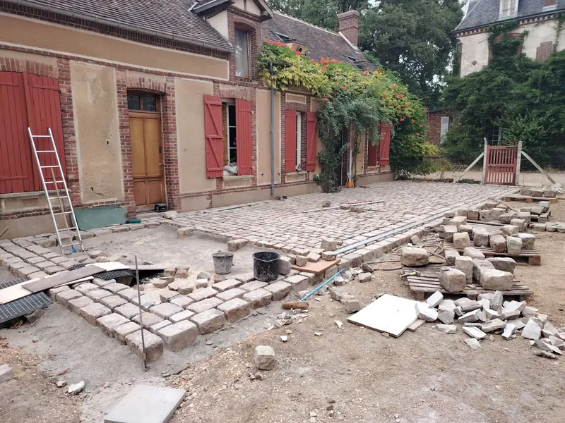 Pose en cours des pavés anciens&nbsp;: la ceinture de gros pavés est en place, le centre se remplit