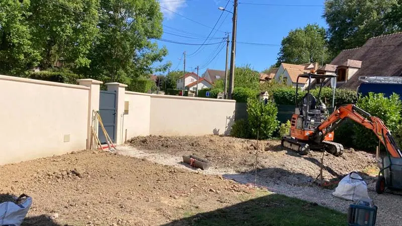 Entrée de maison avant travaux : terre retournée et mini-pelle