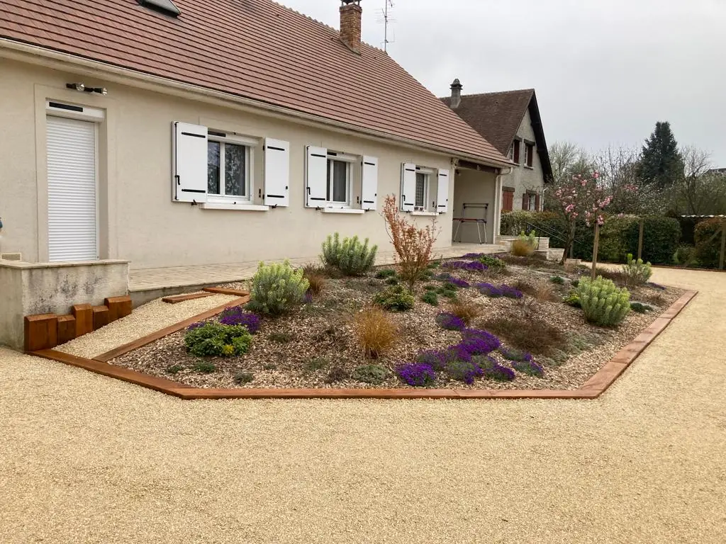 Massif fleuri bordé de traverses au bord de l’allée en gravier stabilisé