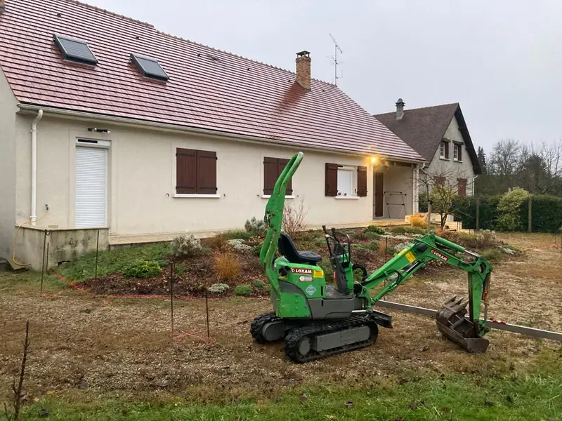 Mini-pelle en cours de terrassement devant la maison