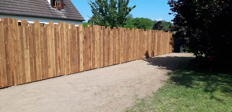 Clôture en bois destructuré le long d’une allée en terre