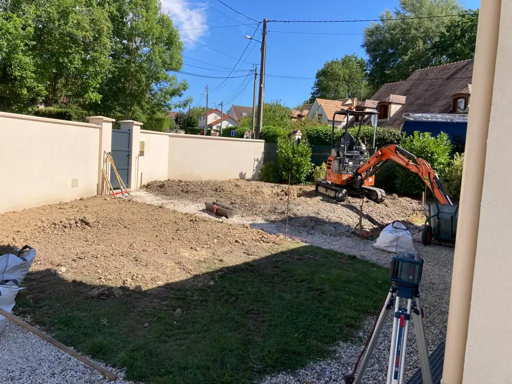 Entrée de maison en terre retournée, mini-pelle au fond, avant travaux