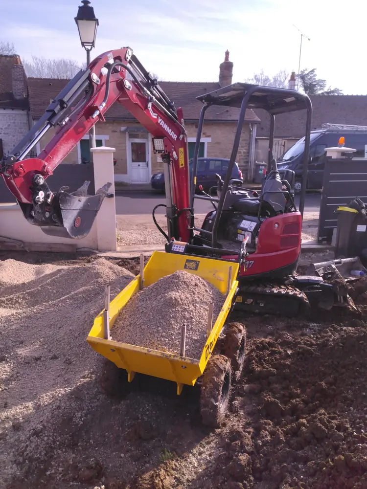 Mini-pelle chargeant un dumper de gravier