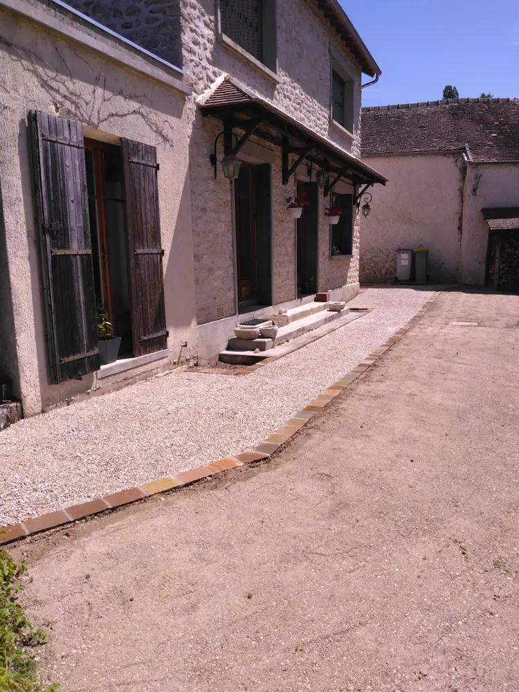 Allée en gravier stabilisé bordée de pavés Kandla devant la maison en pierre