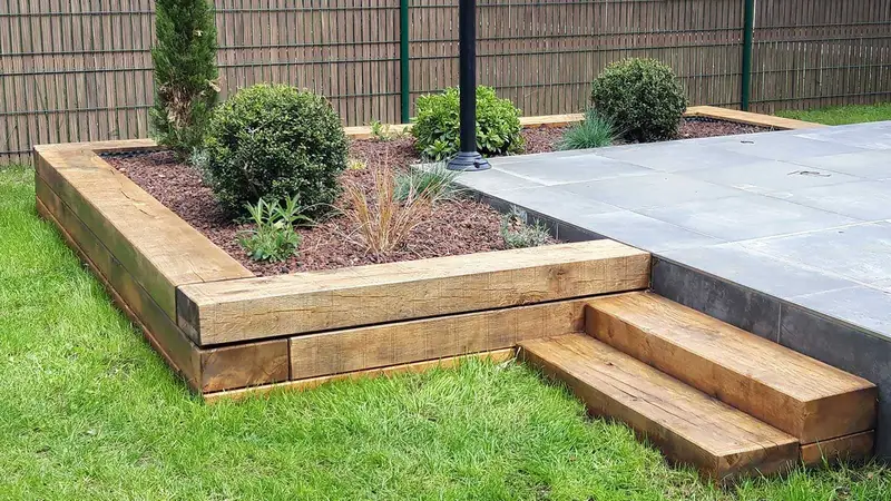 Massif surélevé en traverses et marches en bois au bord d’une terrasse